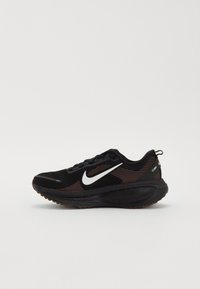 Black athletic shoe with a textured mesh upper, reflective white swoosh logo, and rubber outsole featuring a speckled pattern.
