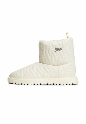 Crèmekleurige doorgestikte enkellaars met dikke geribbelde zool en metalen Tommy Jeans-logo aan de zijkant.