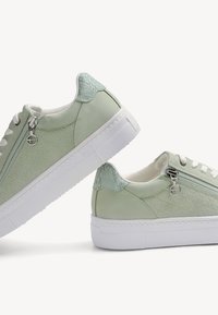 Sneakers verde chiaro con una finitura testurizzata, suola in gomma bianca e dettagli in zip argentati. Presentano una parte superiore in similpelle liscia e accenti in rete.