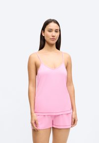 Roosa varrukateta top V-kaeluse ja sobivate lühikestega, mõlemad valmistatud siledast kangast, millel on peen muster ja punased aktsendid.