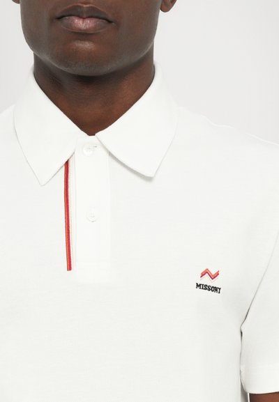 Camisa polo branca com um tecido texturizado, apresentando uma faixa de destaque vermelha e laranja ao longo da casa dos botões e um logótipo bordado "Missoni".