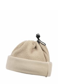 Bonnet en polaire beige avec un cordon de serrage sur le dessus et un revers replié en bas. Texture douce avec une coupe légèrement ample.