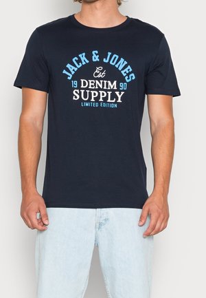 T-shirt en coton bleu marine avec un imprimé graphique en blanc et bleu clair : "JACK & JONES EST 1990 DENIM SUPPLY ÉDITION LIMITÉE." Coupe régulière.