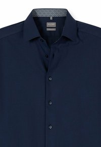 Marineblaue Komfort-Fit-Hemd mit Knopfleiste, schwarzen Knöpfen und gemustertem Innenkragen. Glatte Textur, keine sichtbaren Muster auf dem Körper.