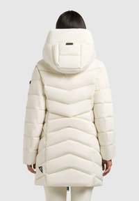 Dikke witte donsjas met een chevronpatroon, een grote capuchon en een ritsluiting. Heeft een klein logopatch nabij de zoom.
