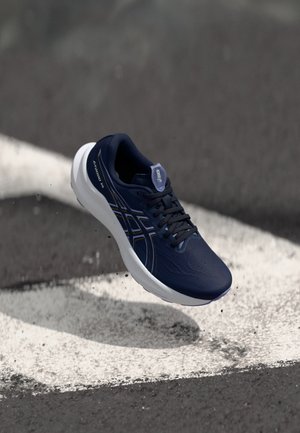Scarpa da running navy con una tomaia liscia e traspirante, suola bianca e logo discreto. Le caratteristiche includono lacci e accenti chiari a contrasto.