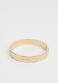Goldener Armreif mit eingraviertem "Lauren Ralph Lauren"-Text und einer Reihe kleiner klarer Steine entlang der Kante. Glatte Oberfläche, elegantes Design.