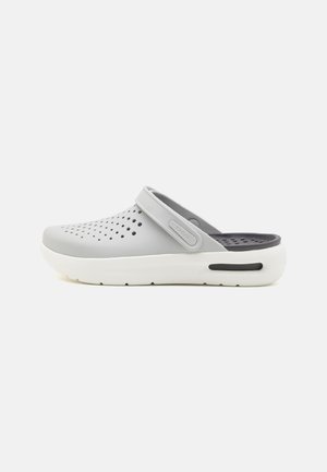 Sabot gris avec un dessus texturé comportant des trous découpés, une sangle arrière et des accents de semelle blanche. Fini lisse et forme ergonomique.
