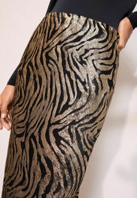 Arany és fekete zebra csíkos szoknya, texturált, fényes felülettel, rugalmas derékkal és karcsú fazonnal.