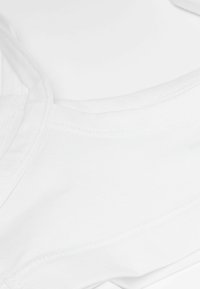 Bílá bavlněná látka s hladkou strukturou, s kulatým výstřihem a jemnými švy. Složení vhodné pro každodenní nošení.