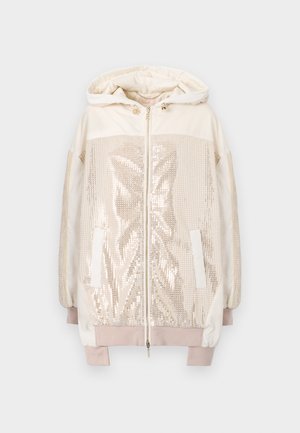 Svetlo bež jakna s kapuco in sprednjim zadrgo, ki se ponaša z bleščicami, velikimi stranskimi žepi in elastičnimi manšetami. Gladka, sijoča tekstura.