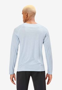 Lichtblauw shirt met lange mouwen, een ronde hals, raglanmouwen en een gladde textuur, gecombineerd met een zwarte broek. Minimalistisch ontwerp.