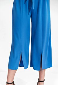 Blauwe culotte-stijl broeken gemaakt van een gladde, lichte stof met zijslits aan de zoom en een relaxte pasvorm.