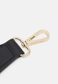 Černý kožený pásek se zlatým kováním, vybavený otočným karabinovým háčkem. Materiál má strukturální povrch, který zdůrazňuje odolnost a styl.