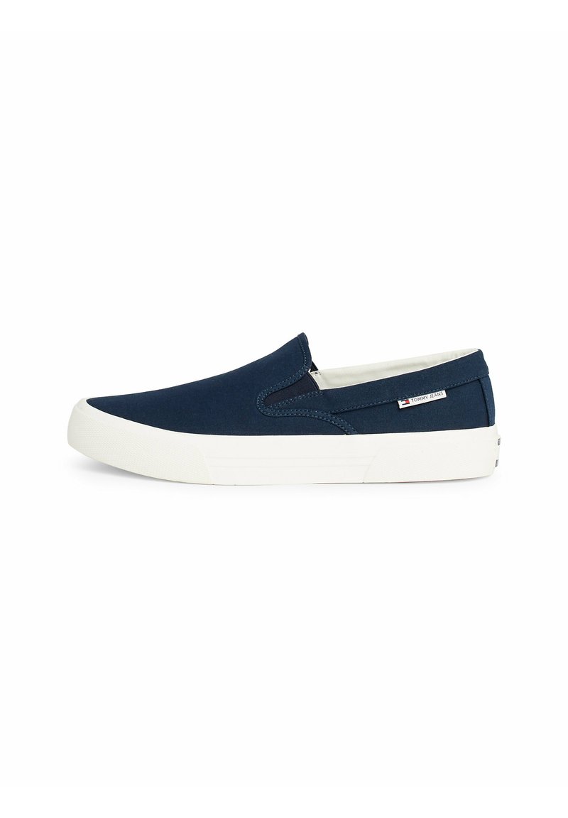 Scarpa in tela navy slip-on con suola in gomma bianca, dotata di pannelli elasticizzati sui lati e di un piccolo tag logo sul tallone esterno.