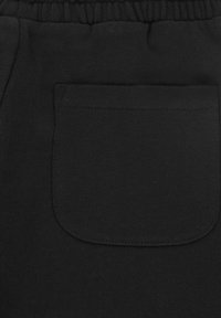 Tessuto di cotone nero con una texture liscia, con una singola tasca rettangolare cucita sul lato destro. Cintura elasticizzata in alto.