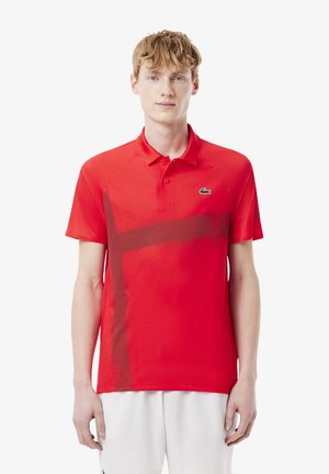 Rotes Poloshirt mit einem Verlaufdesign, das ein schwarzes Logo und ein strukturiertes Streifenmuster auf der Vorderseite aufweist. Kurze Ärmel und Kragen.
