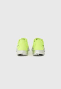 Baskets de course jaune fluo avec un dessus texturé, un talon renforcé et des accents argentés. Elles sont dotées d'une semelle rembourrée avec un motif de semelle distinct.