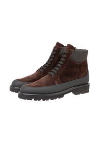 Bruine suede enkellaarzen met grijze rubberen accenten, ronde neus, vetersluiting en een robuuste zool met diepe profielpatronen.