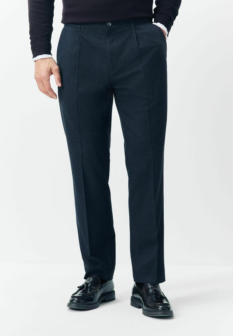 Dark gray tailored pants made of textured fabric, featuring pleats, a button closure, and a straight-leg design, paired with black shoes.