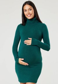 Knit maternity dress in deep green, featuring a ribbed turtleneck, long sleeves, and a form-fitting design that accentuates the belly.