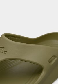 Πράσινο ελιάς σανδάλι slide με λείο, ματ φινίρισμα, διαθέτει ανοιχτό σχέδιο και μια πλευρική τρύπα για αερισμό. Διακοσμημένο με λογότυπο.