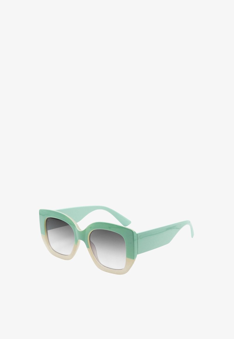 Occhiali da sole verde menta con una montatura spessa e squadrata, caratterizzati da un accento color crema lungo la parte inferiore delle lenti e aste eleganti.