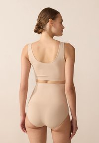 Beige high-waisted briefs and matching crop top made of smooth, stretchy fabric. Minimalist design with wide straps and subtle seams.
