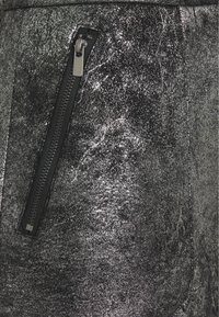 Gonna nera metallica con finitura lucida e testurizzata; presenta una zip laterale in tessuto nero e hardware metallico.