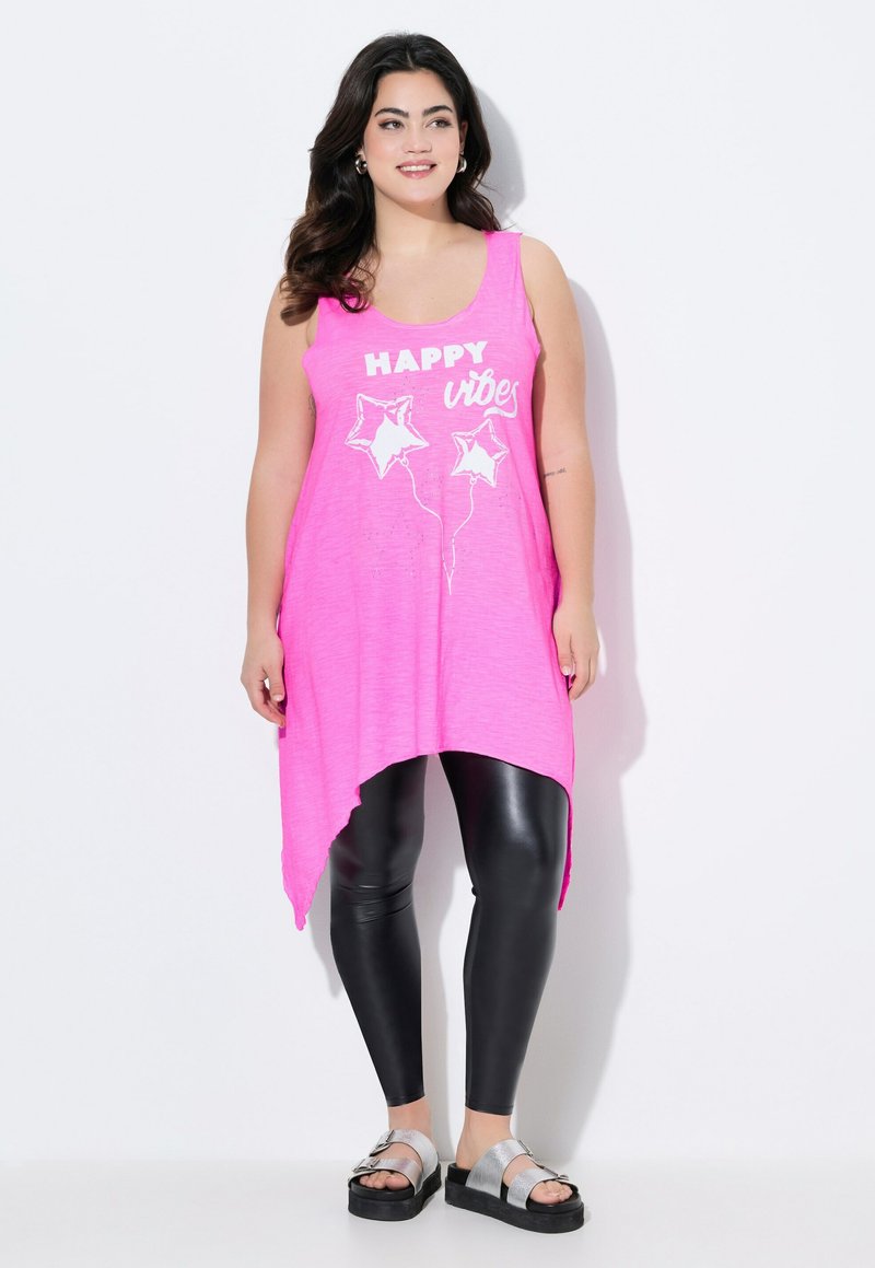 Roze mouwloze tuniek met een high-low zoom, met witte "HAPPY vibes" tekst en sterballon grafieken, gecombineerd met zwarte leggings en zilveren sandalen.