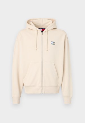 Beige zip-up hoodie gemaakt van een katoenmix. Heeft een hoodie met trekkoord, voorkeurszakken, geribbelde manchetten en een klein logo op de borst.