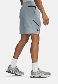 Šviesiai mėlyni sportiniai šortai su juodais užtraukiamais kišenėmis ir „Under Armour“ logotipu šone. Sukurta patogumui ir judrumui.