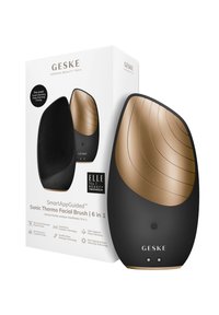 La brosse faciale thermique Sonic, en noir et or, présente une surface en silicone texturé, une forme ergonomique et un design élégant, le tout emballé dans une boîte blanche.