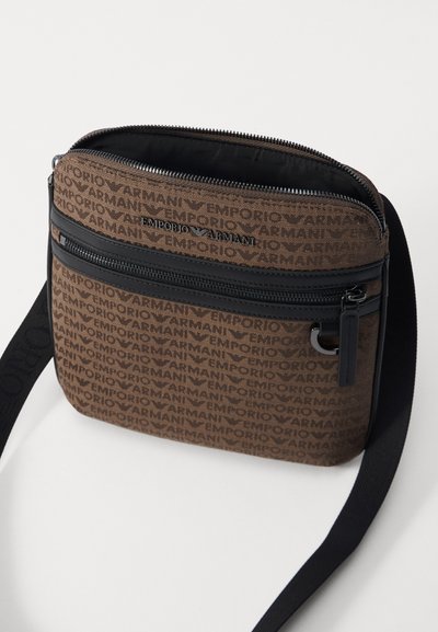 Borsa a tracolla marrone con motivo ripetuto del logo "Emporio Armani", zip nera e tracolla. Presenta un design rettangolare elegante e una texture liscia.