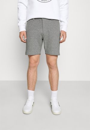 Graue Baumwollmischung-Shorts mit geradem Schnitt, schlichtem Textil und Seitentaschen, kombiniert mit weißen Sneakern und Socken.