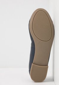 Semelle d'une chaussure bleu marine avec une semelle en caoutchouc beige indiquant la taille 37 et des zones de grip texturées au talon et à l'orteil.