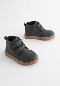 Schwarze synthetische High-Top-Schuhe mit zwei Klettverschlussriemen, runder Zehenpartie und braunen Gummisohlen. Glatte Textur, minimale Nähdetails.