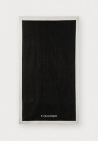Zwarte handdoek met een witte rand en het "Calvin Klein" logo in de rechteronderhoek. Gestructureerde stof met een eenvoudige uitstraling.