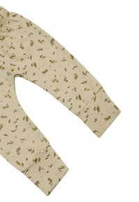 Pantalons en coton beige clair avec un imprimé animal doré sur l'ensemble, présentant des poignets côtelés et une coupe décontractée pour plus de confort.
