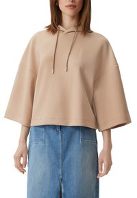 Beżowy krótkoskrócony hoodie ze sznurkiem, szerokimi rękawami i gładką teksturą, w połączeniu z jasnobłękitną spódnicą dżinsową z kieszeniami.