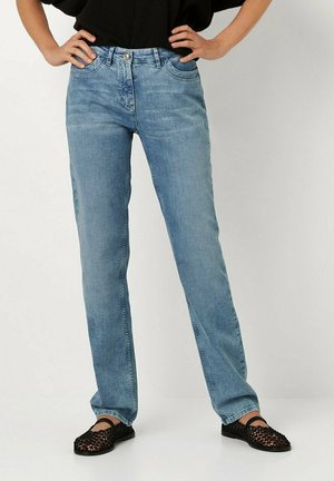 Helles blauesjeans mit geradem Bein, mit subtiler Verblassung, fünf Taschen und einem Knopfverschluss. Kombiniert mit schwarzen geflochtenen Ballerinas.