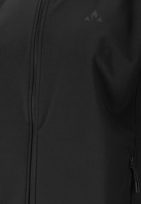 Mustassa vetoketjullisessa takissa on sileä kangas, hienovarainen logo, vetoketjulliset taskut ja tiukka malli.