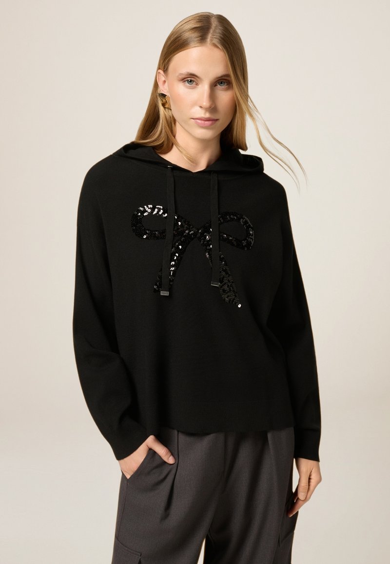 Schwarzer Kapuzenpullover aus weichem Stoff mit einem großen Paillettenbogen-Design auf der Vorderseite, mit Kordelzügen und einer lässigen Passform.