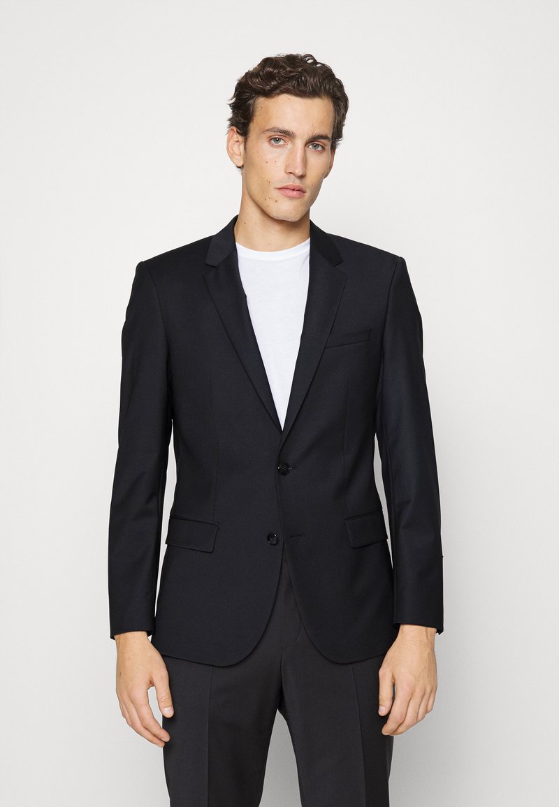 Zwarte op maat gemaakte blazer met twee knopen, gelapte revers, één borstzak en twee zijzakken. Glad stof met een moderne pasvorm.
