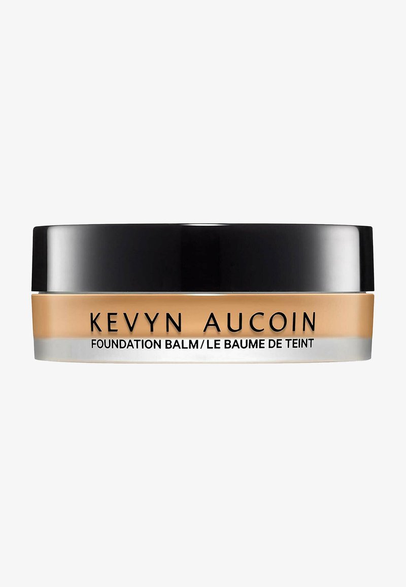 Kevyn Aucoin Foundation Balm in a round container, with a black lid and beige product, features minimal text in bold black font.