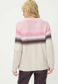Gestrickter Pullover mit einem rosa-weißen Zickzackmuster über den Schultern, das in einen cremefarbenen unteren Bereich übergeht, mit geripptem Saum und Bündchen.