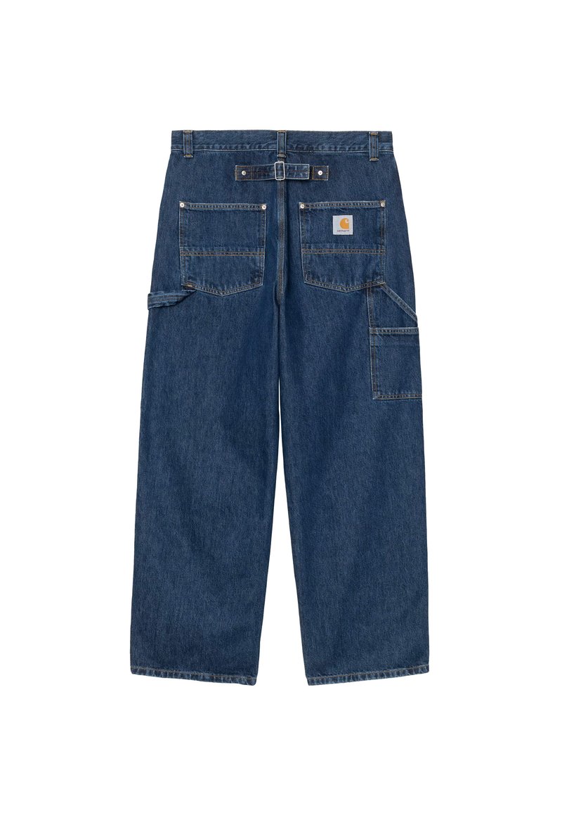 Vue arrière d’un pantalon de travail large en denim bleu foncé avec plusieurs poches et un patch de marque sur la poche droite.