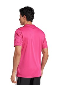 Roze sportshirt van gladde stof, met korte mouwen en een ronde hals. De achterzijde toont een naadloos ontwerp met lichte textuurdetails.