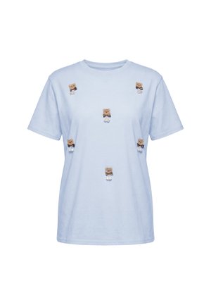 Lyseblå kortærmet t-shirt dekoreret med små bamse-patches spredt over fronten. Ingen synlig baggrund eller yderligere objekter.