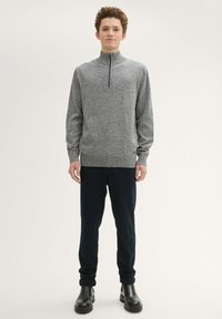Gray, textured sweater with a half-zip collar, paired with dark trousers and black ankle boots. Minimalist design, no noticeable patterns or logos.